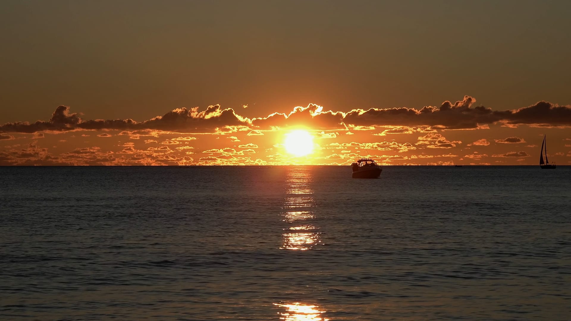 Tief stehende Sonne über ruhigem Meer mit einem kleinen Motorboot